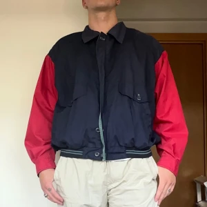 Vintage Colorblock bomberjacka från Private Image/kappahl - Snygg bomberjacka från Private Image med marinblå kropp och röda ärmar. Jackan har två stora fickor framtill, ribbade muddar och dragkedja. Fodret är randigt i rött och grönt. Perfekt för dig som gillar retrovibbar och streetstyle. Hade varit skitsnyggt till några baggy jeans. Sitter som en M, jag är 181cm och väger 80kg för referens. 
