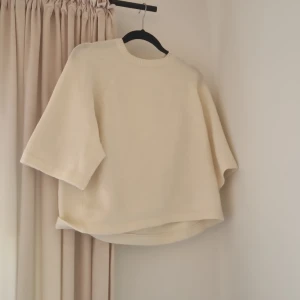 Oversized stickad tröja från UNIQ STUDIO - Superfin oversized stickad tröja från UNIQ STUDIO i en ljus beige färg. Tröjan har rund halsringning och vida trekvartsärmar för en chill och trendig look. Perfekt att styla med jeans eller kjol för en avslappnad vibe.