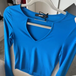 Blå långärmad topp från Bik Bok - Snygg blå långärmad topp från Bik Bok med croppad passform och v-ringad hals. Tillverkad i ett stretchigt och mjukt material som sitter skönt på kroppen. Perfekt att styla med jeans eller kjol för en trendig look.