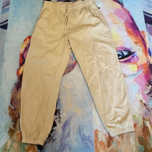 Beiga mjukisbyxor med snöre  - Beiga mjukisbyxor med resår i midjan och benslut samt snörning framtill. 