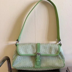 Grön axelväska från Esprit - Snygg ljusgrön axelväska från Esprit med geometriskt mönster och detaljer i grönt skinn. Väskan har ett stilrent spänne framtill och bred axelrem. Perfekt för dig som vill ha en unik och trendig accessoar.