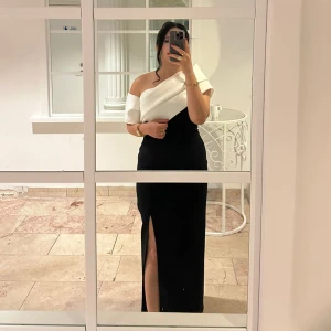 Svartvit långklänning med slits - Säljer en elegant kläning som använt i några timmar ” ordinarie pris 3000kr”. Klänningen har en hög slits framtill som ger en snygg touch. Perfekt för bal eller fest. Sitter tight och markerar midjan. OBS priset kan diskuteras. 