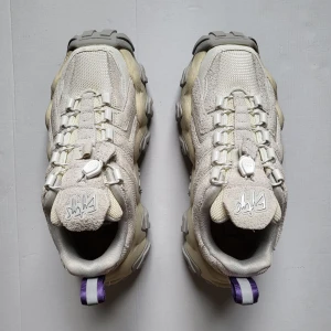 Eytys Halo sneakers i beige och grå - Chunky Eytys Halo sneakers i beige och grå med vågig, kraftig sula och lila hälflik. Ovandel i mocka och mesh med snörning och coola detaljer. Perfekta för dig som gillar statement-sneakers med futuristisk vibe.
