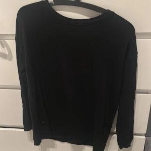 Svart långärmad tröja XS - En basic svart långärmad tröja i enkel och stilren design. Perfekt att matcha med jeans eller kjol för en clean look. Tröjan har rund halsringning och är i en mjuk, tunn kvalitet som känns skön mot huden. Tröjan är i XS men den är i modellen mer luftig än tajt på kroppen💕