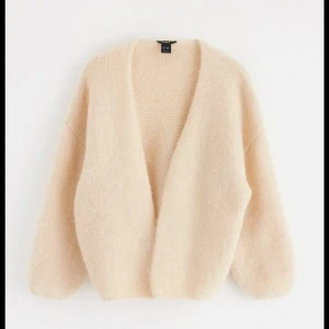 Beige fluffig kofta från Lindex  - Supermjuk och oversized beige kofta från Lindex .Koftan har en öppen front, långa ärmar och är stickad i ett fluffigt material som känns lyxigt och mysigt. Perfekt att slänga på sig när det är kyligt ute.