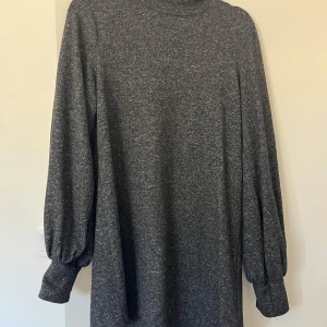 Mörkgrå stickad kortklänning - Mysig mörkgrå stickad klänning med lång ärm och hög hals. 
