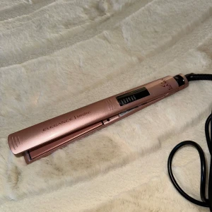 Rosa plattång från Gama - Säljer en elegant rosa plattång från Gama med keratinbeläggning. Den har en smal design och en lång sladd för enkel användning. Perfekt för att skapa släta och glansiga frisyrer.