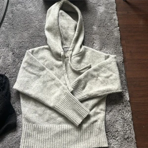 Grå stickad hoodie - Säljer en mysig grå stickad hoodie från Zara med ribbade muddar och nederkant. Perfekt för kyliga dagar med sin bekväma passform och klassiska design. Huvan har justerbara snören för extra komfort.🩷