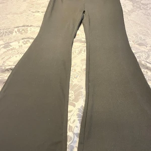 Svarta byxor med rynkad detalj - Snygga svarta byxor med en rynkad detalj vid midjan. Byxorna har en bootcut-stil som ger en trendig look. Perfekta för en stilren outfit. Testat endast en gång men de var för långa. Skulle säga 160-165 i längd, kan sy upp snyggt men för ett dyrare pris.