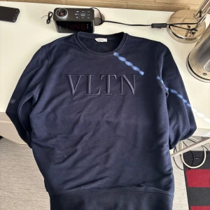 Mörkblå tröja från Valentino - Säljer en snygg mörkblå tröja från Valentino med VLTN-logga på bröstet. Tröjan har en klassisk rund hals och långa ärmar. Perfekt för en stilren look.