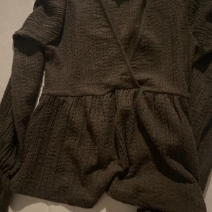 Brun omlottopp från Gina Tricot - Säljer en brun omlottopp från Gina Tricot som är aldrig använt o köpt för ca en vecka sedan. Toppen har långa ärmar och en volangdetalj vid midjan. Perfekt för en stilren look. 🤎