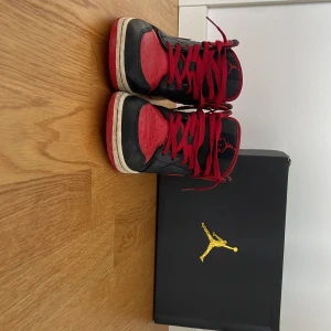 Nike Air Jordans i rött och svart - Snygga Nike Air Jordans i klassisk röd och svart färgkombination. Skorna har snörning och en rund tå, perfekt för en sportig look. De kommer med originalkartong. De är väl använda och har en slitning på sulan, se bild. 