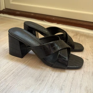 Svarta klackskor med krokodilmönster - Snygga svarta klackskor med ett elegant krokodilmönster. Skorna har en bred klack och öppen tå. 