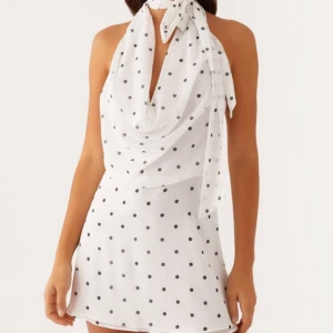 Vit prickig klänning - Snygg vit klänning med svarta prickar och halterneck-design. Klänningen har en öppen rygg och knytband vid halsen som kan knytas på olika sätt (tex som scarf eller vanlig halterneck) klänningen är i nyskick och super trendig så säljer endast vid bra bud💕💕😍