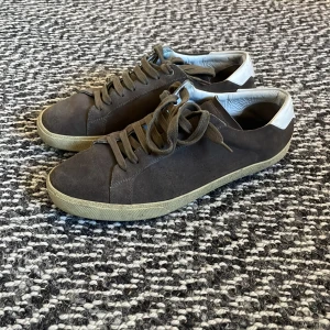 Bruna YSL skor - Snygga bruna sneakers i mocka med vit häl och snörning. Perfekta för en avslappnad stil. De har en rund tå och en bekväm sula som ger bra stöd. De har dock ingen innersula så det måste man skaffa själv.