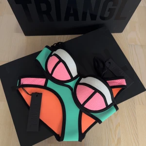 Turkos/Rosa Triangl Bikini (Oanvänd) - Säljer en äkta oanvänd Triangl Bikini. Storlek XS på överdel och XXS på underdel. Box till bikinin finns om man önskar få med den, dock blir paketet större och därav dyrare frakt.