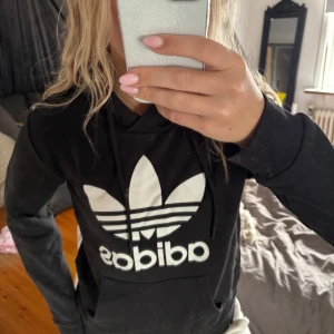 Svart hoodie från Adidas - Säljer en svart hoodie från Adidas med den klassiska loggan i vitt på framsidan. Fint skick!❣️