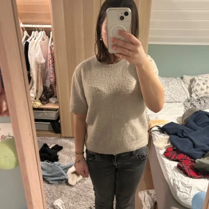 Beige stickad tröja - Säljer en stilren beige stickad tröja med korta ärmar. Perfekt för en avslappnad look. Tröjan har en rund hals och en bekväm passform.