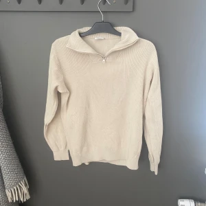 Beige stickad tröja från Kappahl - Säljer en stilren beige stickad tröja från Kappahl. Tröjan har en dragkedja vid halsen och långa ärmar. Perfekt för kyligare dagar. Passar både till vardags och mer avslappnade tillfällen.