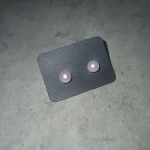 Rosa pärlörhängen - Säljer ett par söta rosa pärlörhängen. Perfekta för att ge en subtil touch av färg till din outfit. De är små och eleganta, vilket gör dem lätta att bära till olika tillfällen.