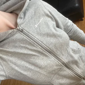 Grå zip-hoodie från Champion - Säljer en klassisk grå hoodie med dragkedja från Champion. Tröjan har huva, fickor framtill och logga på bröstet.💕