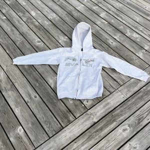 Grå hoodie från Bvaldi - Säljer en stilren grå hoodie från Bvaldi med dragkedja framtill. Tröjan har en bekväm huva och långa ärmar, perfekt för kyliga dagar. Den är tillverkad i ett mjukt material som känns skönt mot huden.org pris 1100 vs mitt pris 400, pris går att diskutera 
