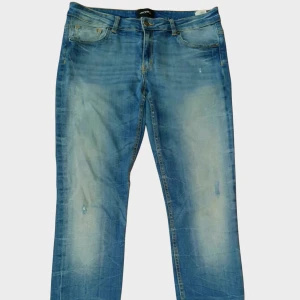 Jeans från Monki – Storlek L - Klassiska jeans i blå denim från Monki. Rak passform med lätt tvättade partier för en stilren men avslappnad look. Jeansen har traditionell femficksdesign samt dragkedjor vid bensluten som en snygg detalj.  Storlek: L Skick: Fint begagnat skick 