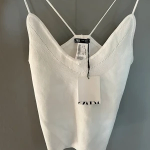 Vit linnetopp från Zara - Snygg vit linnetopp från Zara med smala axelband och en stilren design. Perfekt för varma dagar eller som ett lager under en jacka. Toppen har en enkel och elegant look.