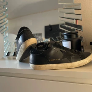 Svarta sneakers från Golden Goose - Snygga svarta sneakers från Golden Goose med en stjärndetalj på sidan. Skorna har en klassisk design med snörning och en vit sula som ger en cool kontrast. Perfekta för en stilren look.