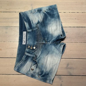 Snygga Black Bat jeansshorts - Ursnygga low-waist jeansshorts från Black Bat. Unika sömmdetaljer, nitar och fickor. Väldigt bra skick dock liten fläck (bild1) går nog bort. Köpta på Vinted. Verkligen bästa sommarshortsen. 🌅