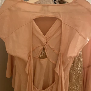 Ljusrosa klänning med knytning - Söt ljusrosa klänning med knytning framtill och öppen rygg i bak med två band.💖