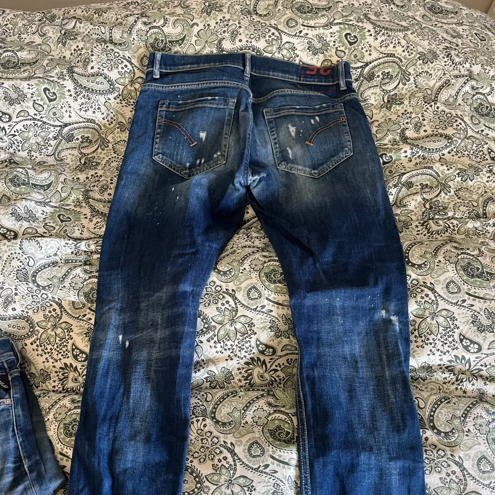 Säljer ett par snygga blå jeans från Dondup med slitna detaljer och en klassisk femficksdesign. Jeansen har en normal passform och är tillverkade i denim med en lätt tvättad look. Perfekta för en avslappnad stil. . Farkut & Housut.