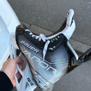 Bauer Vapor Hyperlite X hockeyskridskor - Säljer ett par Bauer Vapor Hyperlite X hockeyskridskor i svart, silver och vit. Skridskorna har snörning och är designade för maximal prestanda på isen. Perfekta för dig som vill ha snabba och lätta skridskor med grym passform.