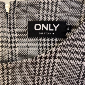 Rutig klänning från ONLY - Säljer en snygg grå och svart rutig klänning från ONLY i storlek S. Klänningen har trekvartsärm, rund halsringning och dragkedja bak. Den är figurnära och kort i modellen, perfekt för dig som gillar klassisk stil med modern twist. (Aldrig använd) Nypris 299kr