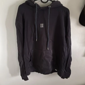 Marinblå hoodie från Les Deux - Säljer en stilren marinblå hoodie från Les Deux med en enkel design och en liten logga på bröstet. Tröjan är i gott skick och perfekt till våren. Nypris 800kr, mitt pris 250kr