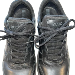  Ecco Gore-Tex stl 39 - Snygga svarta sneakers från Ecco med snörning och Gore-Tex-material för extra skydd mot väta. Skorna har en robust sula med röd detalj för bra grepp och komfort. Perfekta för vardagsbruk och håller dina fötter torra och bekväma.