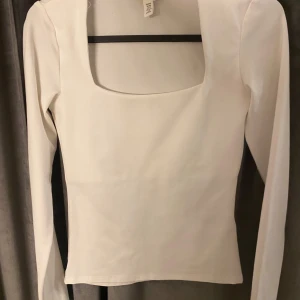 Vit långärmad topp med fyrkantig ringning - Säljer en stilren vit långärmad topp från H&M med snygg fyrkantig ringning. Nästan aldrig använd i st xs