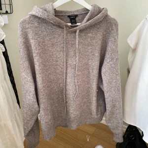 Beige hoodie från Lindex - Mysig beige hoodie från Lindex i mjukt stickat material. Tröjan har långa ärmar, huva med dragsko och ribbade muddar vid ärmslut och nederkant. Perfekt för en avslappnad och stilren look.
