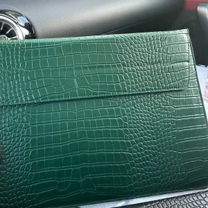 Mörkgrön kuvertväska  - Säljer en stilren mörkgrön kuvertväska från Celestio.se. Väskan har en elegant och slät design med lock och passar perfekt för att bära laptop eller dokument. ✨NU FÖR ENDAST 200kr!✨