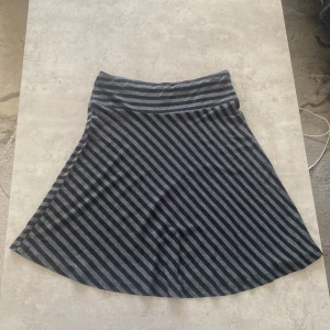 Randig kjol från H&M - Säljer en snygg randig kjol från H&M i svart och grått. Kjolen har en bekväm passform och är perfekt för en avslappnad stil. Tillverkad i Turkiet.