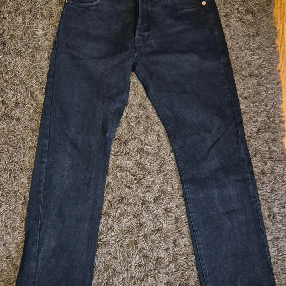 Klassiska mörkblå Levi's 501 jeans med raka ben och femficksdesign. Byxorna har normal passform och är tillverkade i slitstarkt denim. Perfekta för dig som gillar tidlös stil och vill ha ett par jeans som funkar till det mesta.. Farkut & Housut.