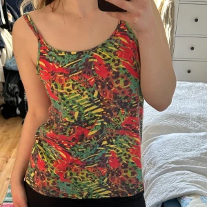Färgglad linne med leopardmönster - Säljer en färgglad linne med leopardmönster i rött, grönt och gult. Linnet har smala axelband och en avslappnad passform. Perfekt för en somrig look!
