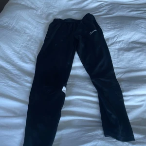 Svarta träningsbyxor från Nike - Säljer ett par svarta träningsbyxor från Nike med elastisk midja och vita detaljer. Perfekta för träning eller en avslappnad dag. Byxorna har en klassisk passform och är gjorda i ett mjukt material för extra komfort.