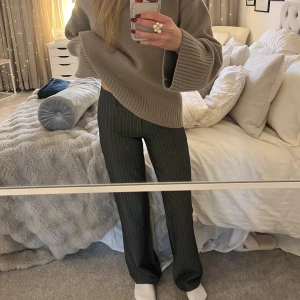 Randiga kostymbyxor - Snygga kostymbyxor med smala ränder i en mörk färg. Byxorna har en klassisk passform och är perfekta för en stilren look. De är högmidjade och har en rak stil som ger en elegant siluett.Midjemått: 36 , innerbenslängd: 78