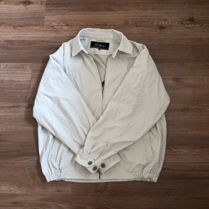 Oscar Jacobson overshirt - Säljer en snygg och stilren overshirt/tunn jacka i en vit beige färg. Den är i ett bra skick utan defekter. Storleken är L men sitter som M, förstor på mig så mått kan fås om de behövs. Perfekt nu till våren och sommaren. Priset kan diskuteras!