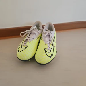 Nike Phantom fotbollsskor i gul och vit - Säljer ett par Nike Phantom fotbollsskor i en fräsch gul färg med vita och svarta detaljer. Skorna har snörning och är designade för att ge bra grepp på planen. Perfekta för dig som vill sticka ut på fotbollen!