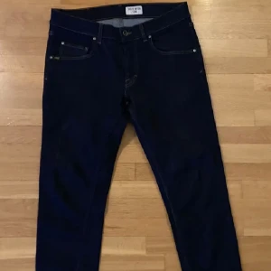 Mörkblå jeansbyxor från Tiger of Sweden - Säljer ett par mörkblå jeans i 31/32 från Tiger of sweden. Byxorna har smal passform och raka ben. Sparsamt använda och är i mycket fint skick.  