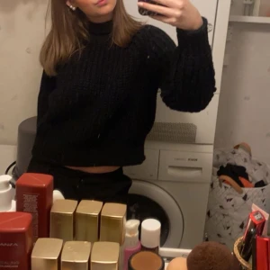 Svart stickad croppad tröja - Säljer en svart stickad croppad tröja med grov ribbstickning och lång ärm. Perfekt till jeans eller kjol för en chill och snygg look. Hög hals och mjukt material.