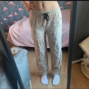 Beiga linnebyxor från Zara Woman - Säljer ett par beiga linnebyxor från Zara Woman med dragsko i midjan. Byxorna har avslappnad passform och raka ben, perfekta för varmare dagar. Lätta och luftiga med elastisk midja och snörning framtill.
