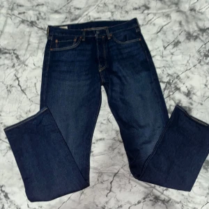 Levi's 501 mörkblå jeans 32/32 - Klassiska Levi's 501 jeans i mörkblå denim med raka ben och femficksmodell. Byxorna har gylf med knappar och tydliga kontrastsömmar. Perfekta för dig som gillar tidlös stil och hög kvalitet. Byxan är ej använd.